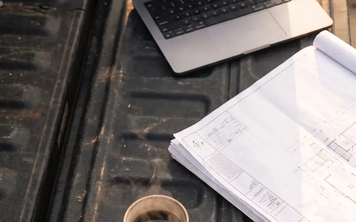 Laptop and printed plans on a job-site tailgate